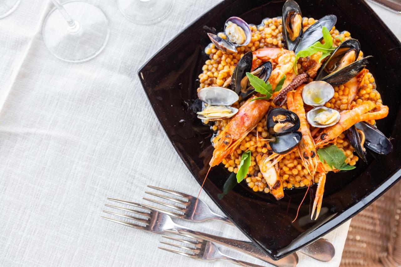 Een bord met eten, zeevruchten en maïs, op tafel. bij Abamar Hotel in Santa Margherita di Pula