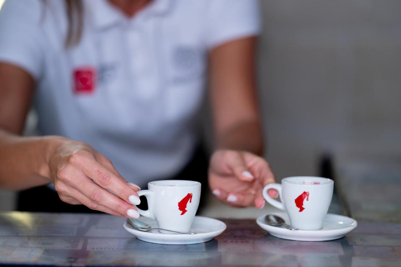 een vrouw met twee koffiekopjes op een tafel bij BADIA NUOVA Apart Hotel in Trapani
