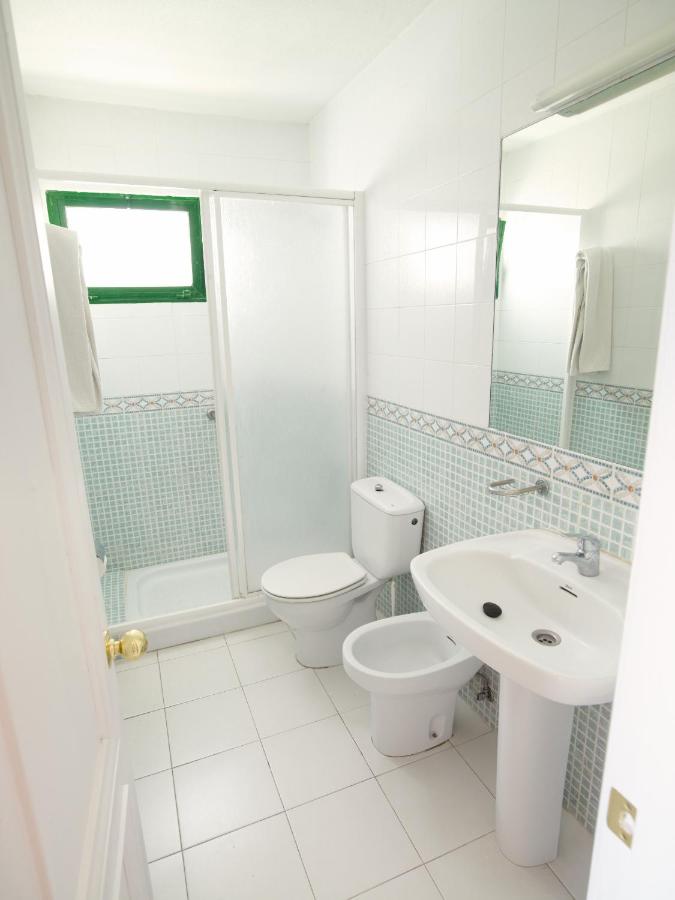 een witte badkamer met een toilet en een wastafel bij Apartamentos Babalu in Puerto Rico de Gran Canaria