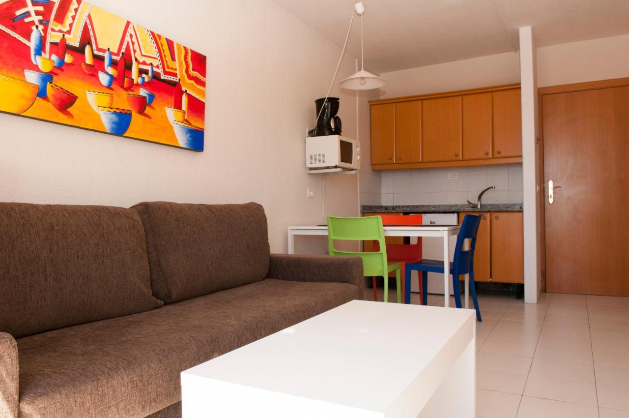 een woonkamer met een bank en een keuken bij Apartamentos Babalu in Puerto Rico de Gran Canaria