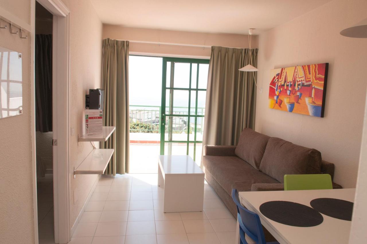 een woonkamer met een bank en een tafel bij Apartamentos Babalu in Puerto Rico de Gran Canaria