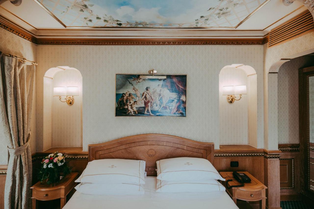 een slaapkamer met twee bedden en een schilderij aan het plafond bij River Palace Hotel in Rome