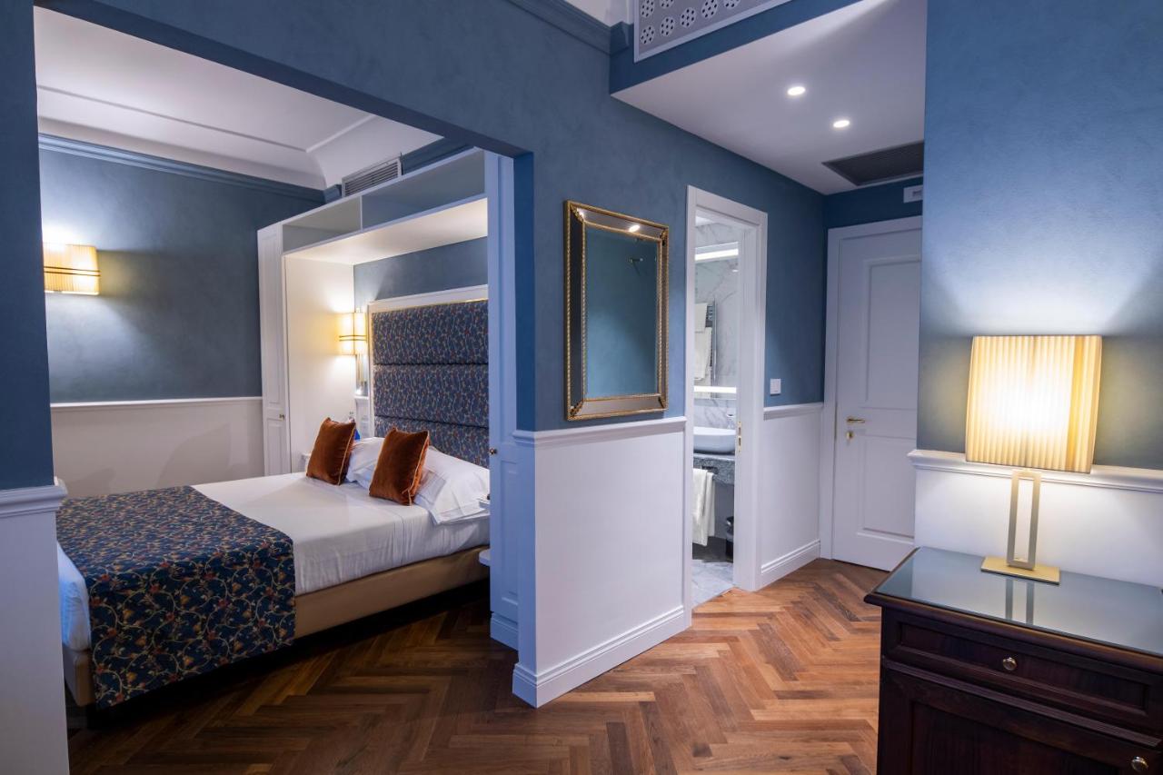 een slaapkamer met blauwe muren en een bed met een spiegel bij Rivoli Boutique Hotel in Florence