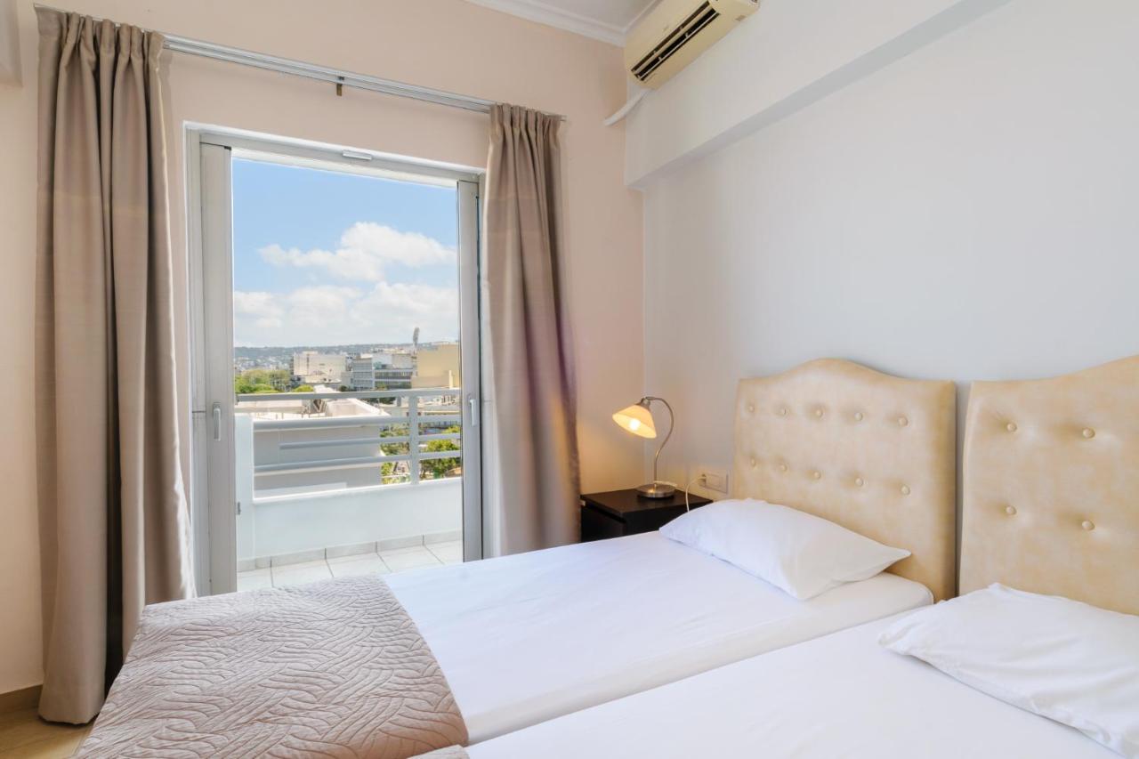een slaapkamer met twee bedden en een groot raam bij Archontiki City Hotel in Chania