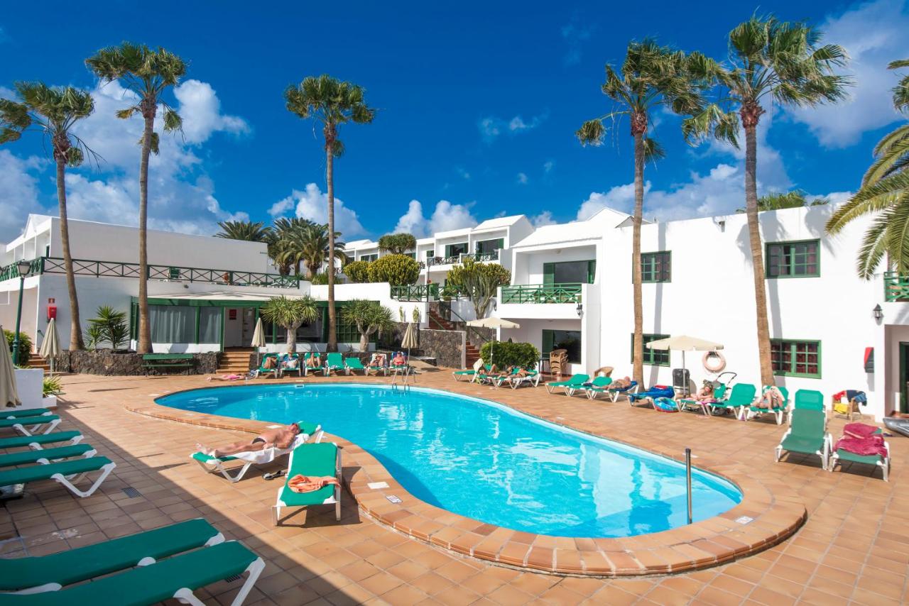 een zwembad bij het resort met mensen die in ligstoelen zitten bij Rocas Blancas Apartments in Puerto del Carmen