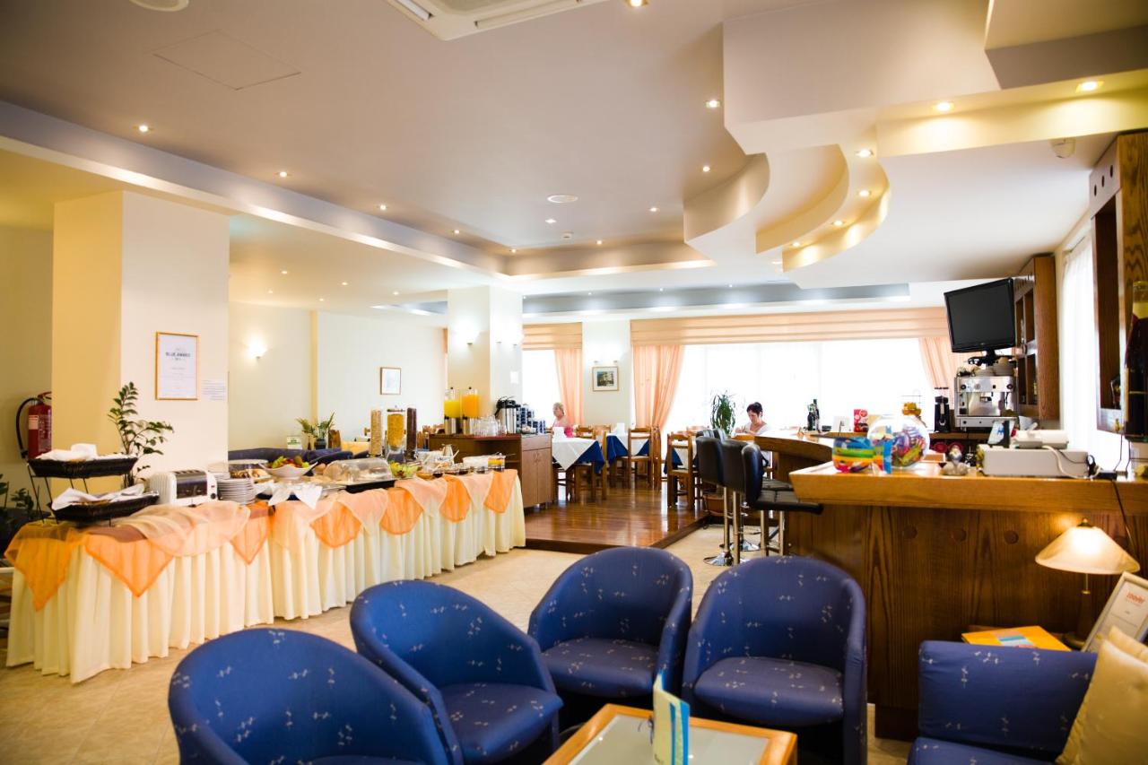 een wachtkamer met blauwe stoelen en een bar bij Astali Hotel in Rethimnon