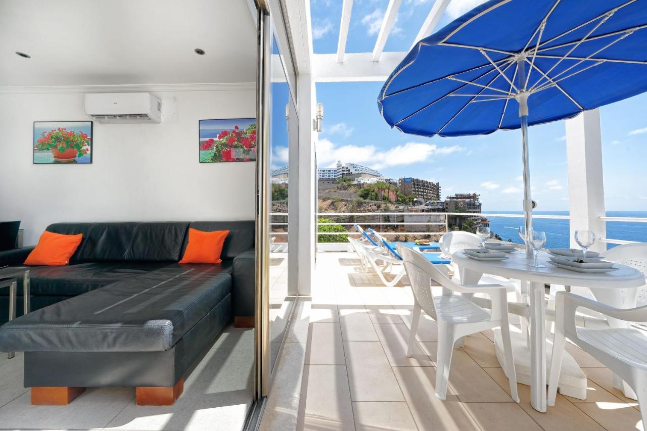 een woonkamer met een bank en een tafel met een parasol bij Ona Bahia Blanca in Puerto Rico de Gran Canaria