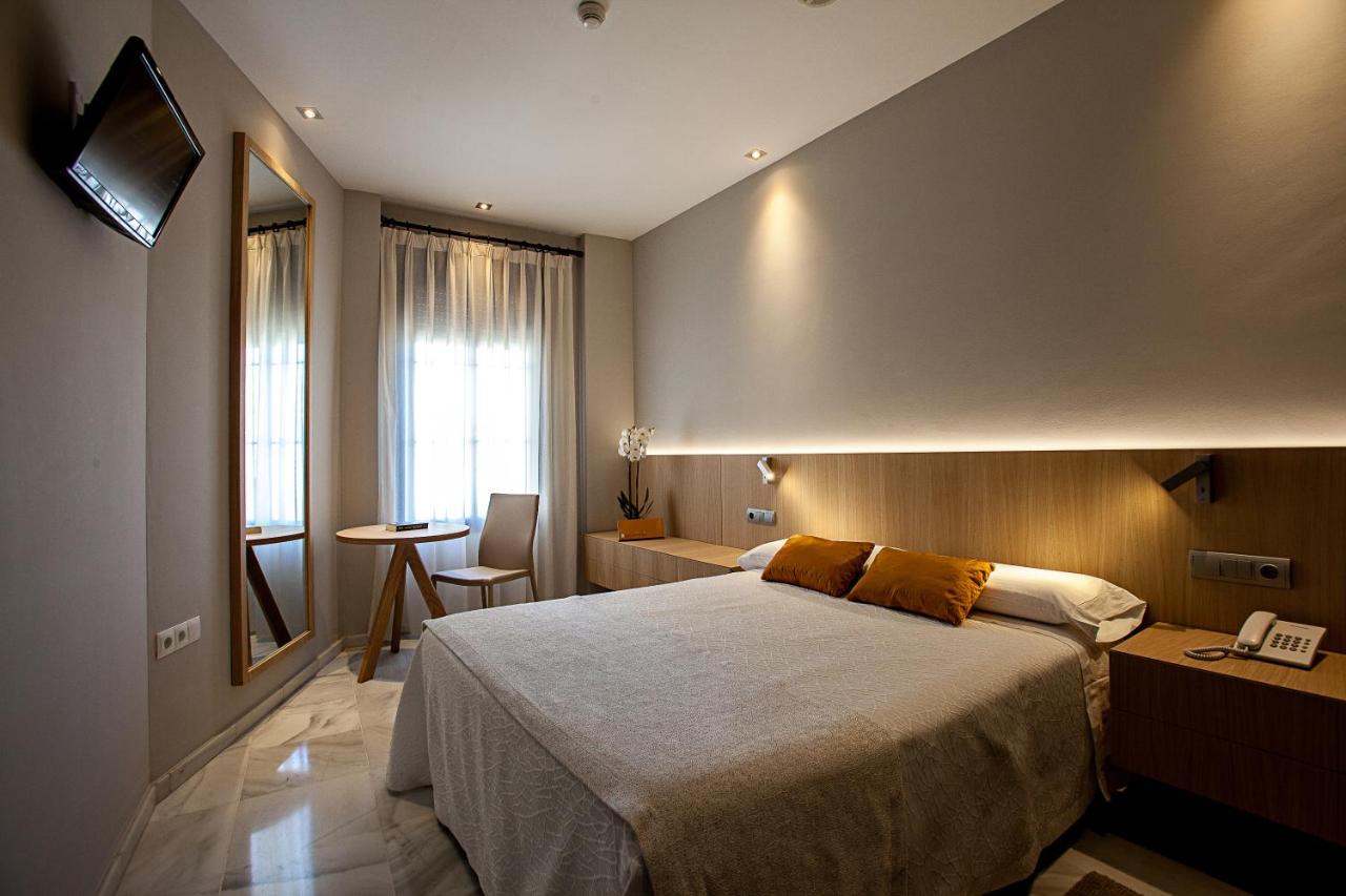 een slaapkamer met een groot bed en een tafel bij Hotel Barrameda in Sanlúcar de Barrameda