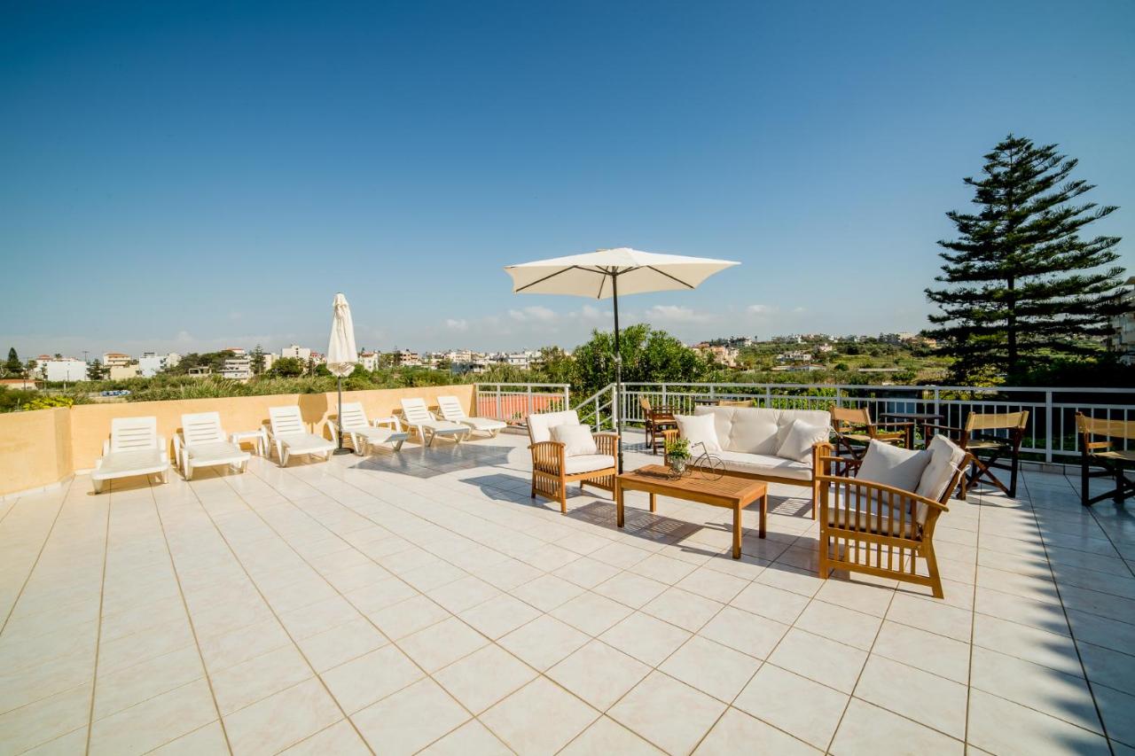 een terras met een aantal stoelen en een parasol bij Roxani Hotel in Amoudara Herakliou