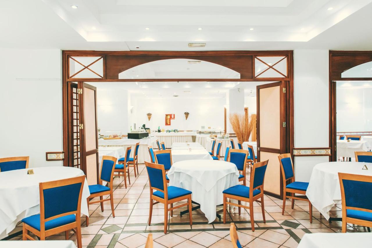 een eetkamer met witte tafels en blauwe stoelen bij Hotel Royal Positano in Positano