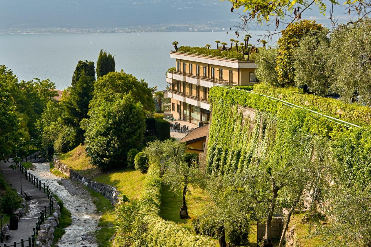een gebouw dat bovenop een heuvel naast een rivier staat bij Hotel Royal Village in Limone sul Garda
