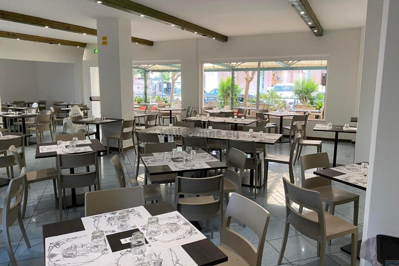 een eetkamer vol tafels, stoelen en ramen bij Hotel Aron Rimini in Rimini