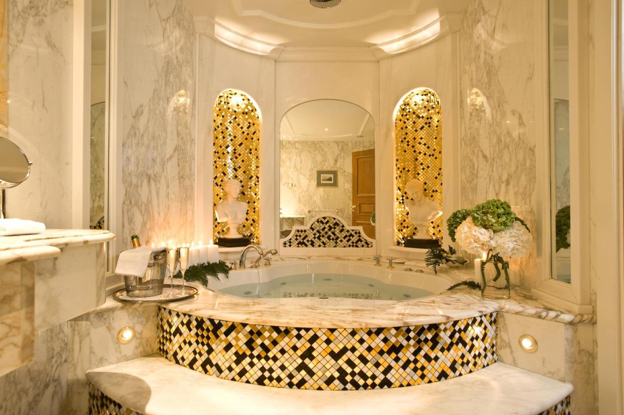 een badkamer met een badkuip met een grote spiegel bij Royal Olympic Hotel in Athene