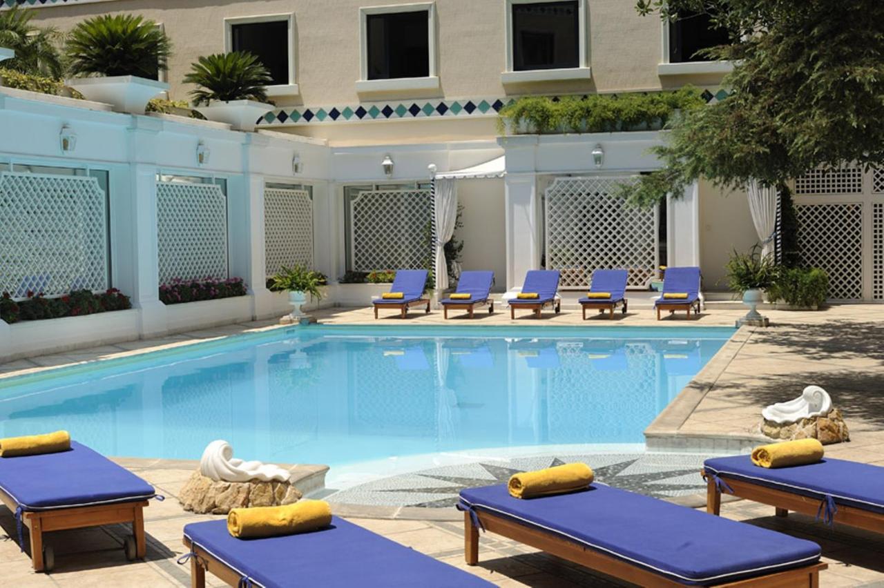 een zwembad met ligstoelen en een hotel bij Royal Olympic Hotel in Athene