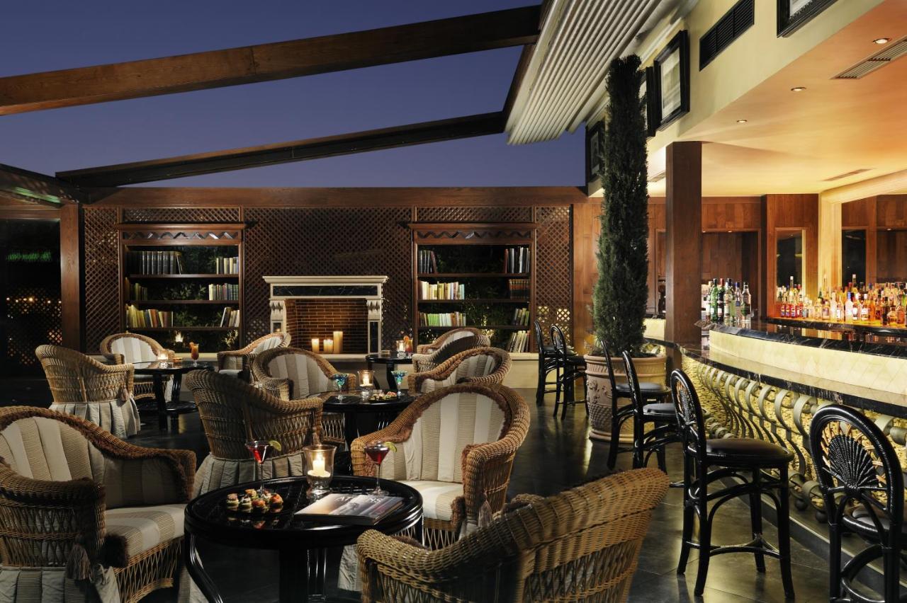 een restaurant met rieten stoelen en tafels en een bar bij Royal Olympic Hotel in Athene