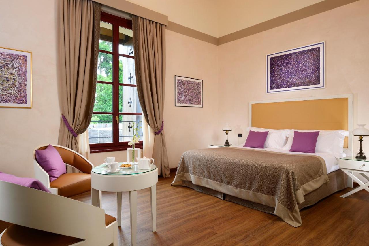 een hotelkamer met een bed, een stoel en een tafel bij Castello Dal Pozzo Resort Lago Maggiore - Preferred Hotels & Reso