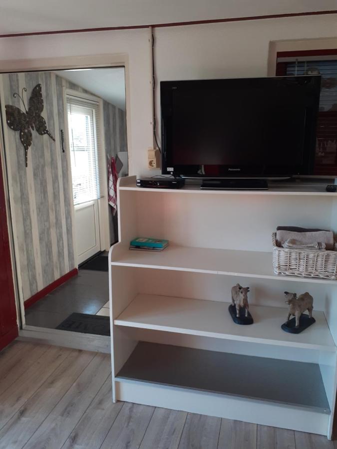 een woonkamer met een tv op een witte plank bij Dirosa in Onderdijk