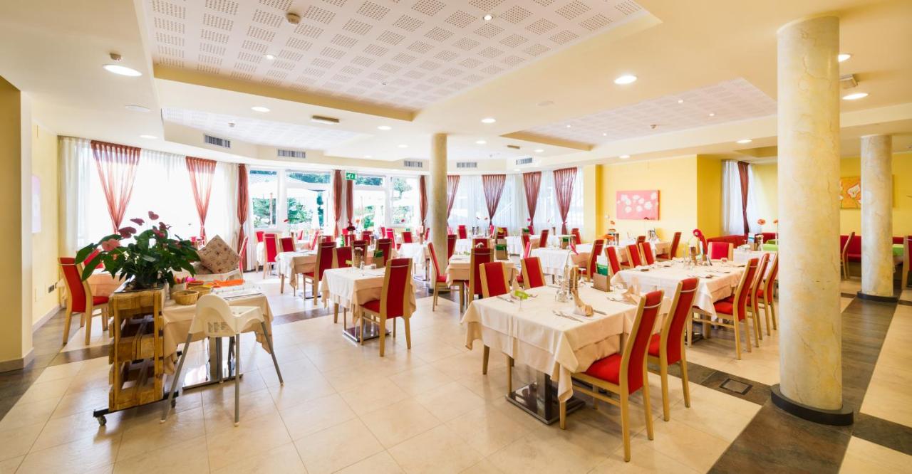 een restaurant met witte tafels en rode stoelen bij Nature Bio Hotel Elite in Levico Terme