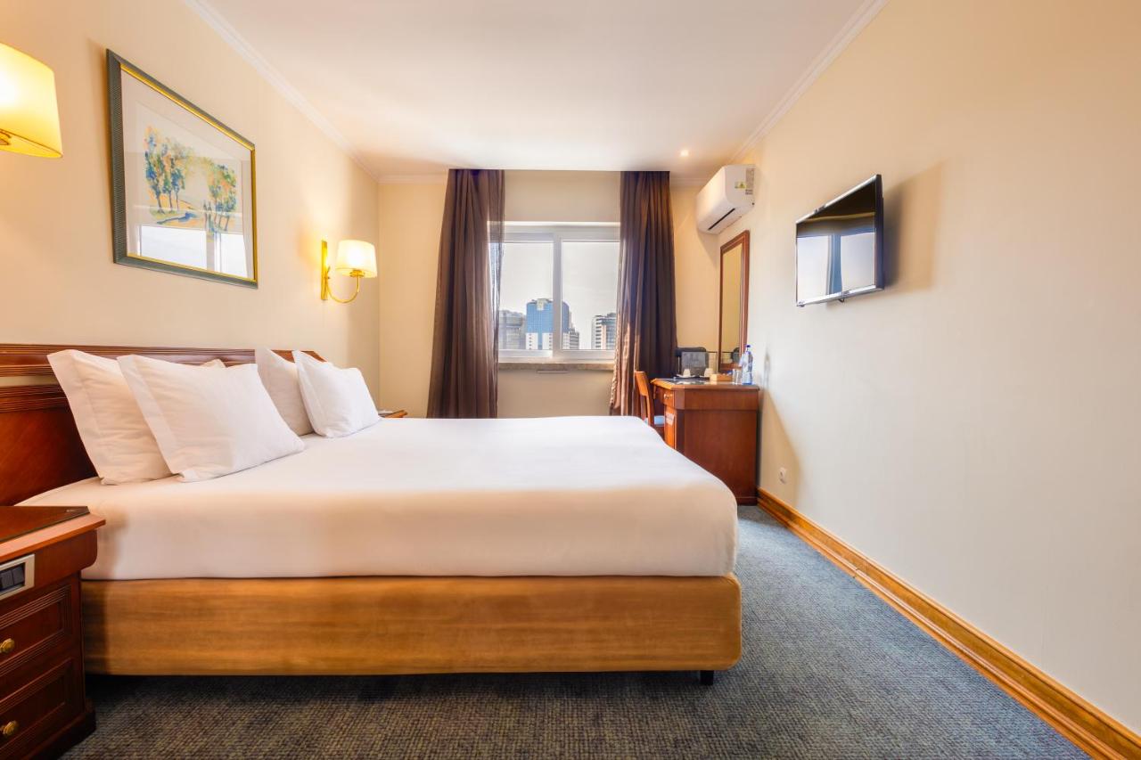 een hotelkamer met een bed en een raam bij SANA Rex Hotel in Lissabon