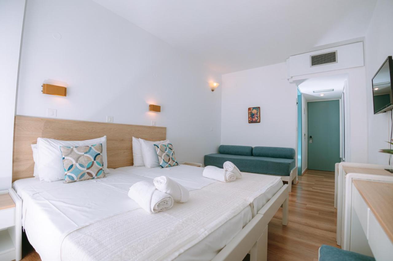 een slaapkamer met een groot bed en een groene bank bij Santa Marina Unique Hotel in Agios Nikolaos