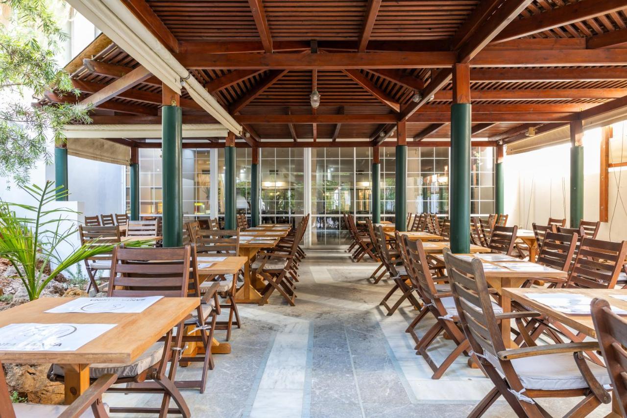 een leeg restaurant met houten tafels en stoelen bij Santa Marina Unique Hotel in Agios Nikolaos