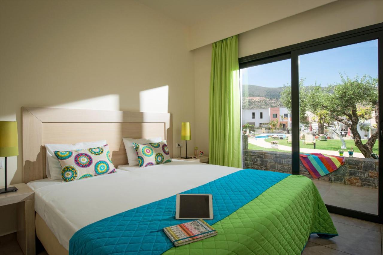 een slaapkamer met een groot bed en een groot raam bij Kristalli Hotel Apartments in Malia