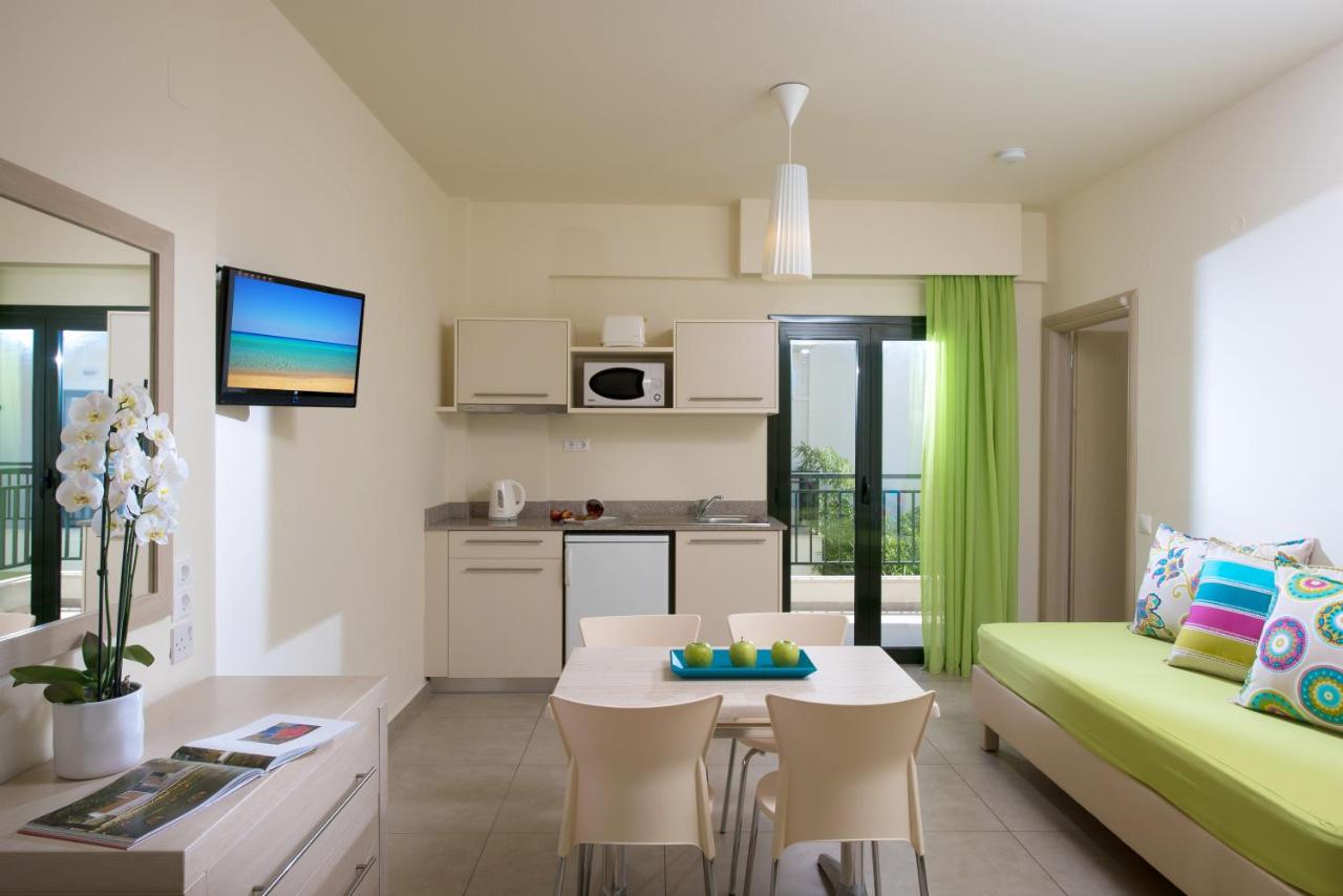 een woonkamer met een groene bank en een keuken bij Kristalli Hotel Apartments in Malia