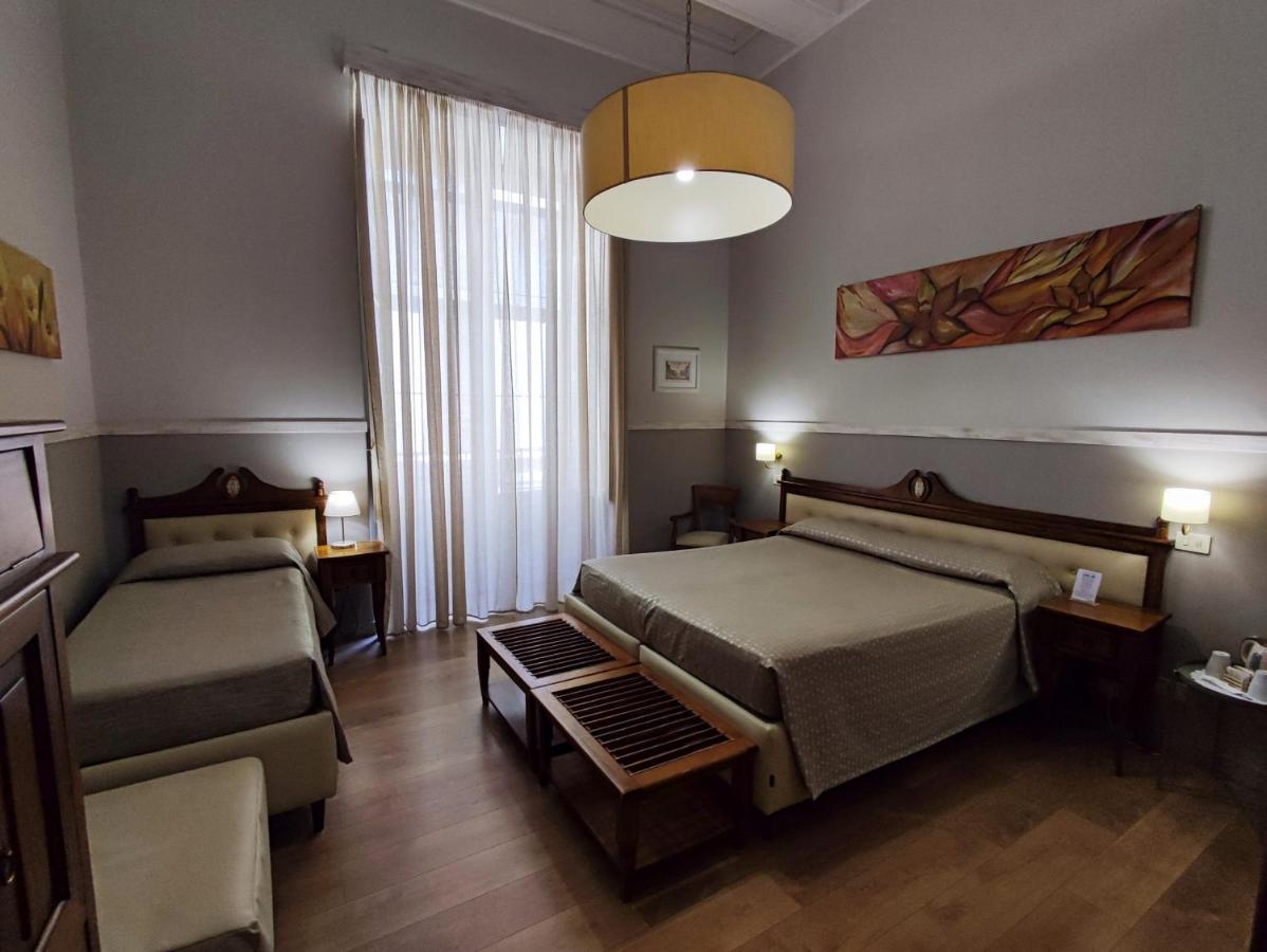 een slaapkamer met twee bedden en een bank bij La Collegiata Guest House in Catania