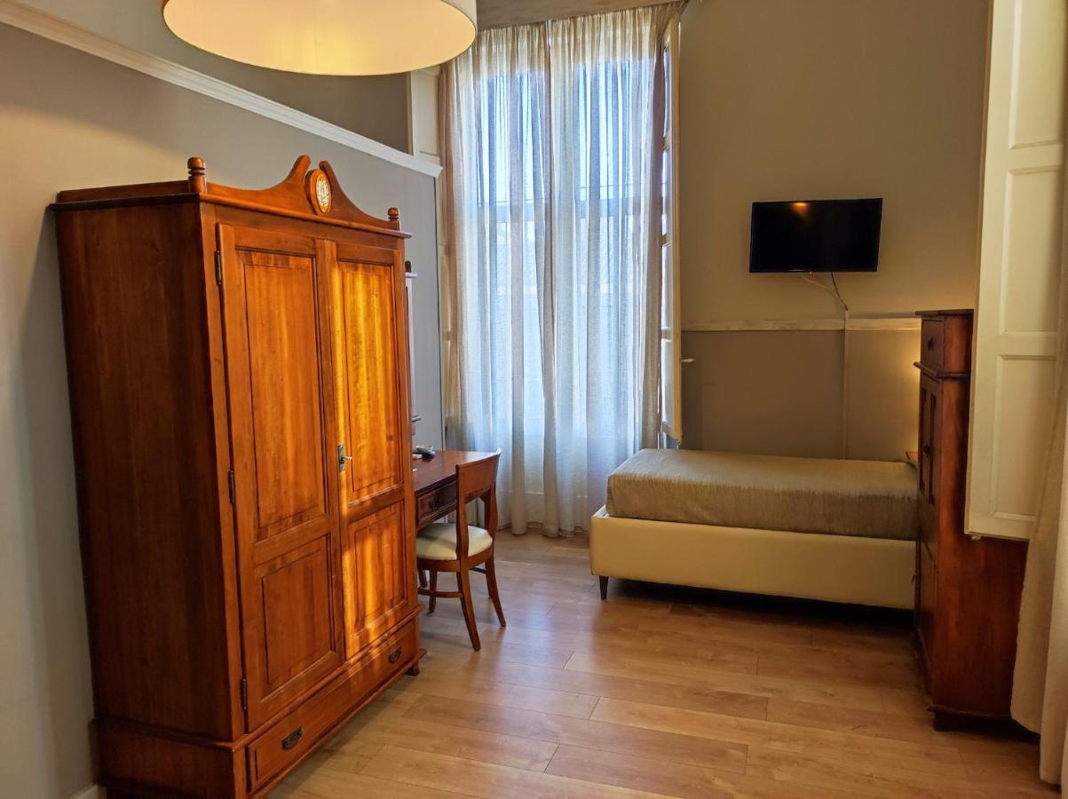 een slaapkamer met een bed, een houten kast en een bureau bij La Collegiata Guest House in Catania