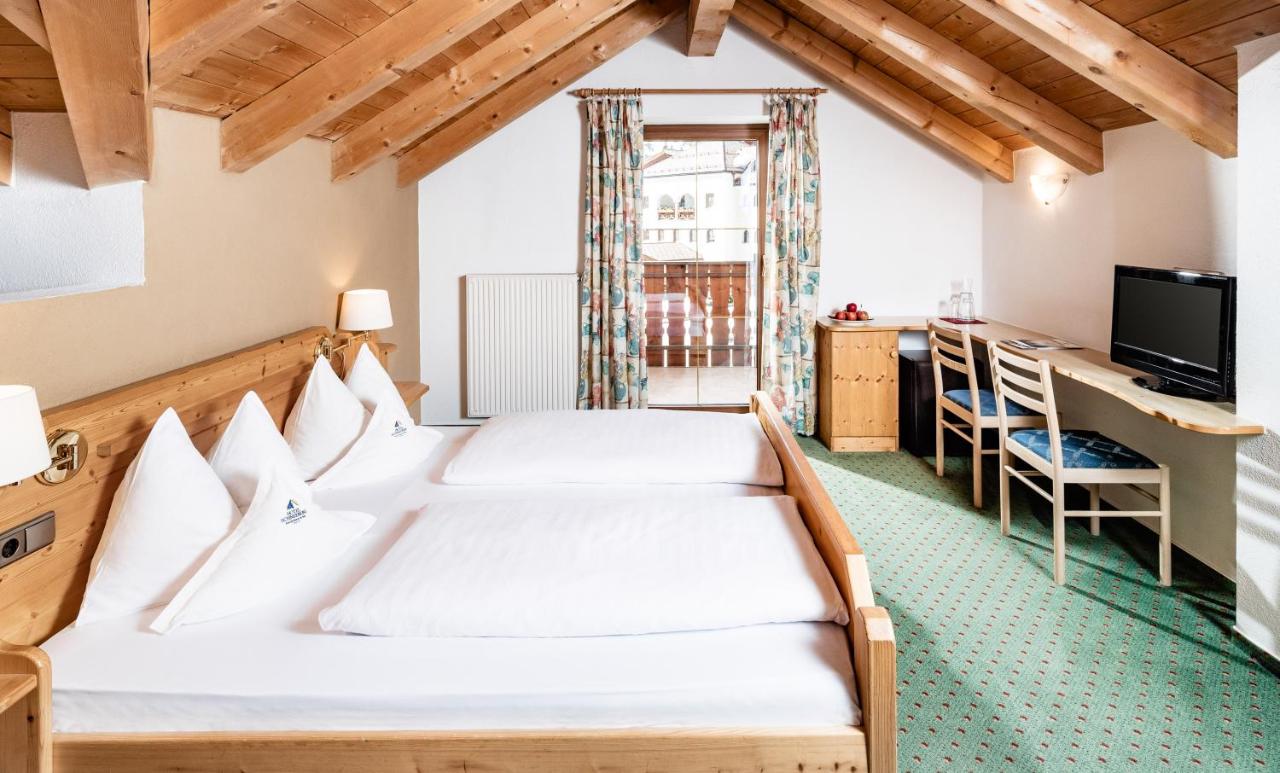 een slaapkamer met twee bedden en een bureau bij Hotel Schneeberg FAMILY SPA RESORT in Ridanna
