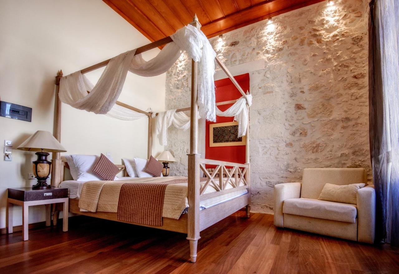 een slaapkamer met een hemelbed en een stoel bij Leo Hotel in Rethimnon