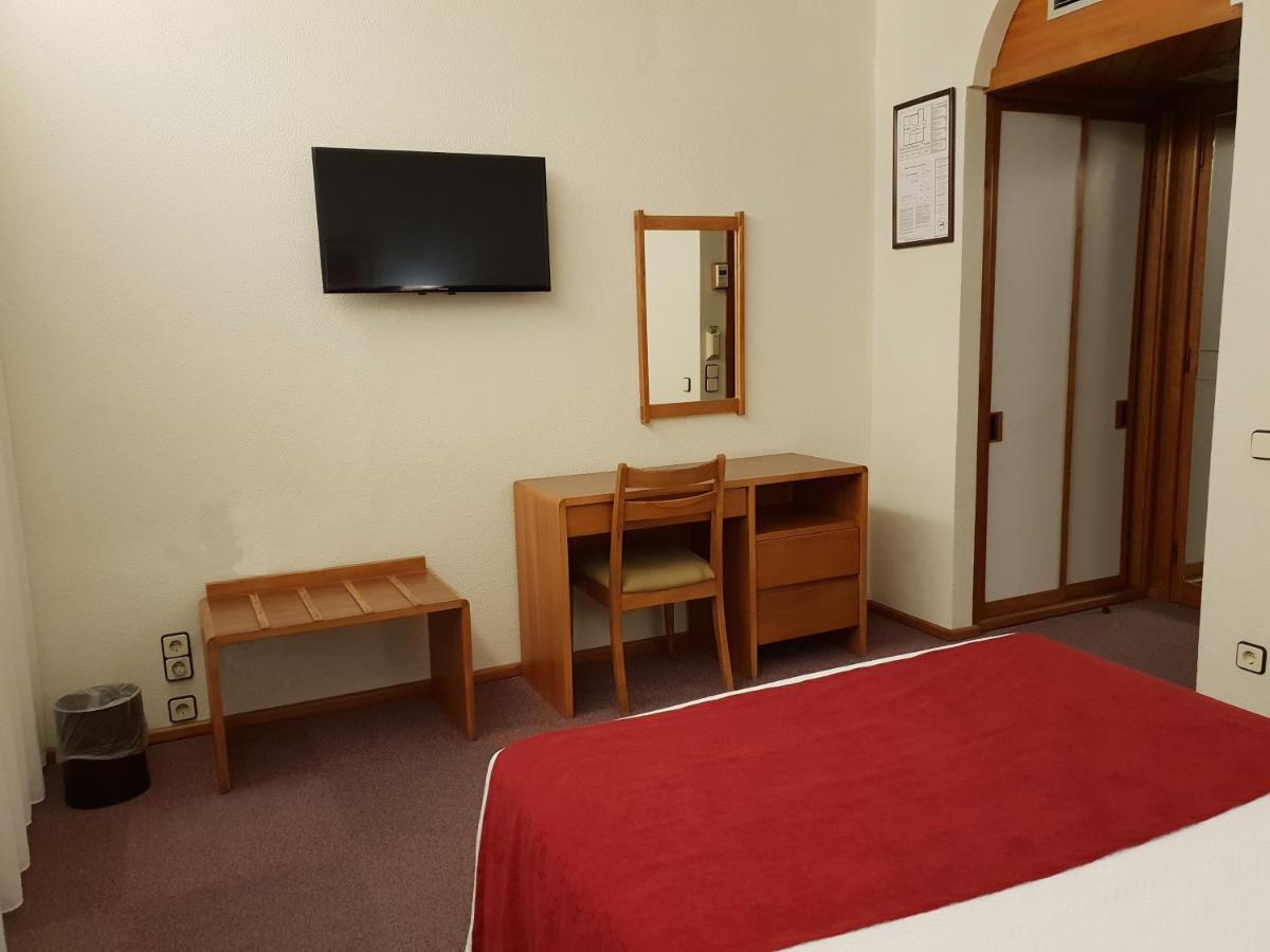 een slaapkamer met een bureau en een televisie aan de muur bij Luso Brasileiro in Póvoa de Varzim