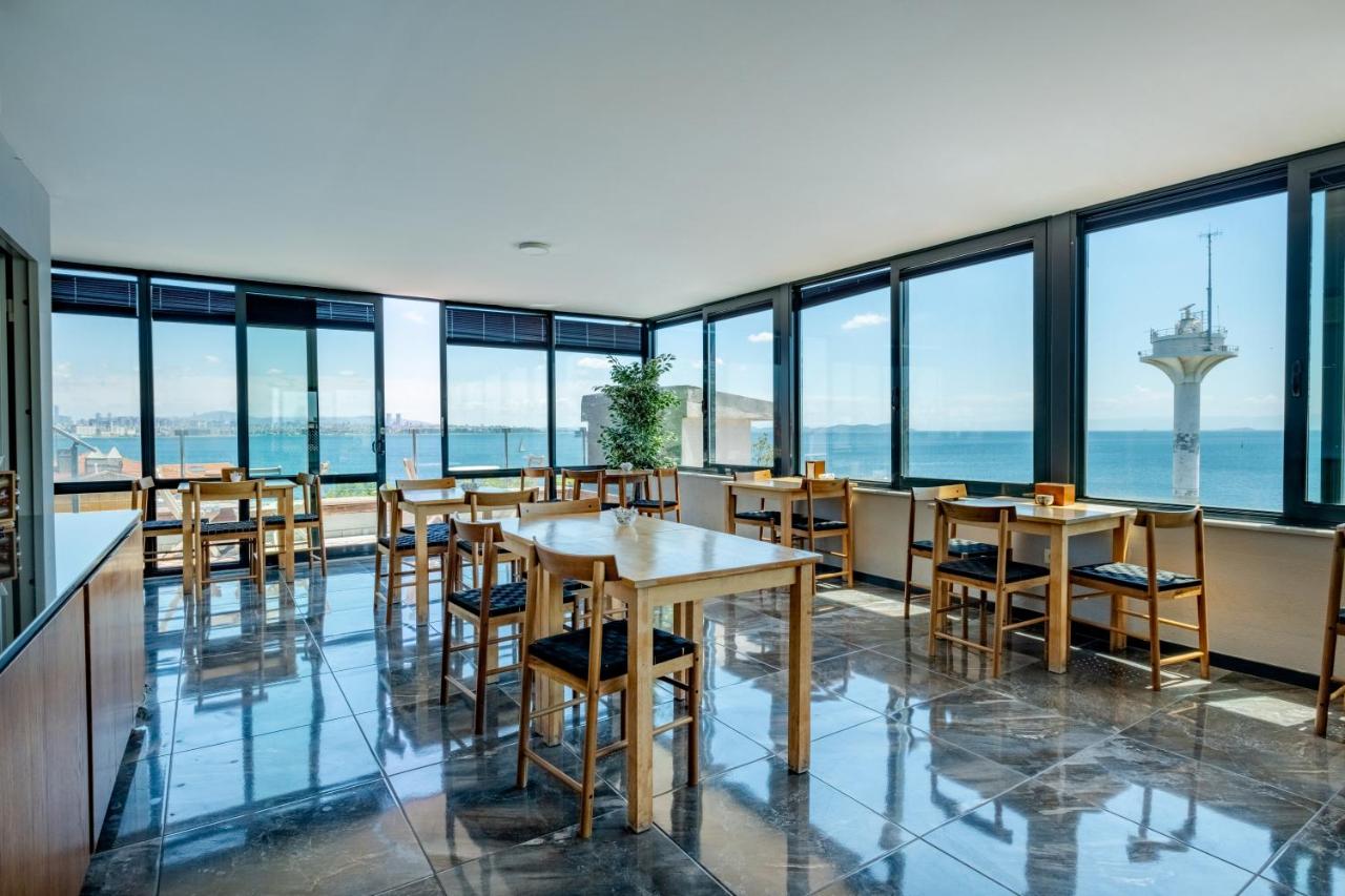 een restaurant met tafels en stoelen en grote ramen bij Mangana Konak Hotel in Istanbul