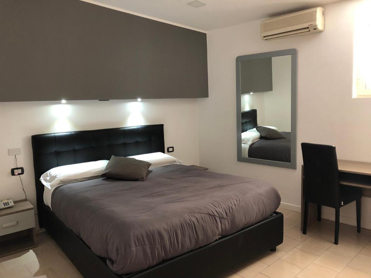 een slaapkamer met een bed, een bureau en een spiegel bij Hotel Nettuno in Napels