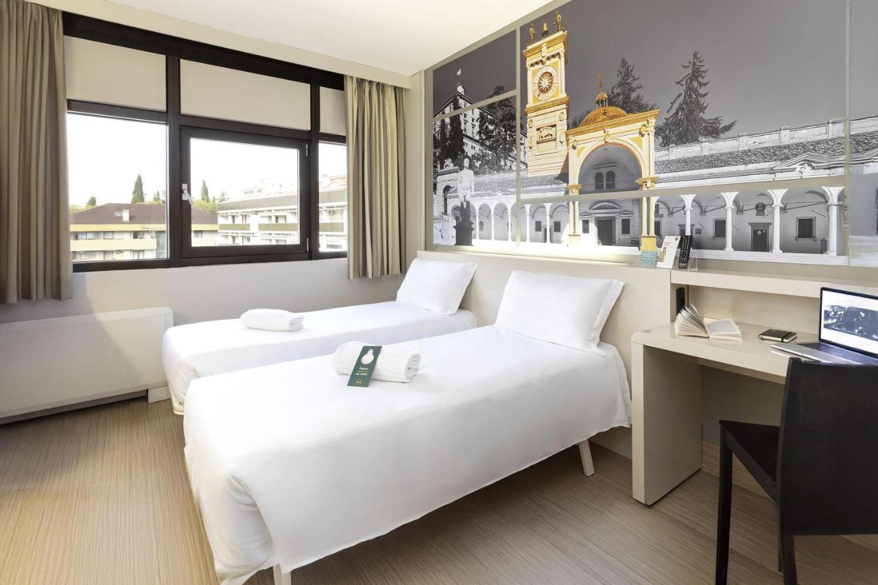 een hotelkamer met twee bedden en een bureau bij B&B Hotel Udine in Udine