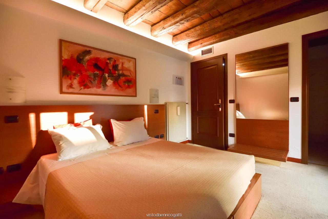 een slaapkamer met een groot bed met witte kussens bij Hotel Quo Vadis in Udine