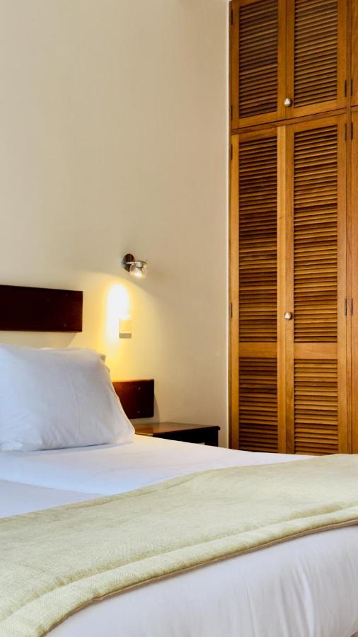 een slaapkamer met een bed en een houten kast bij Traineira Vila Ventura Village in Caniço