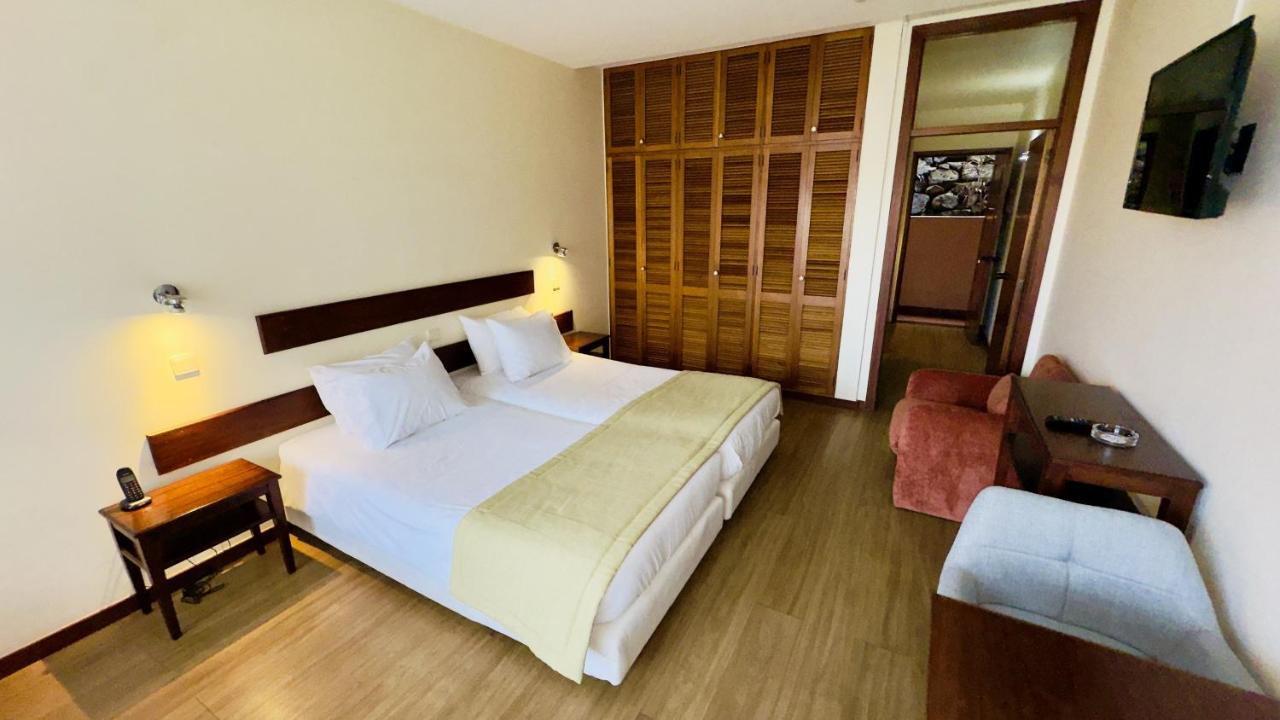 een slaapkamer met een groot wit bed en een stoel bij Traineira Vila Ventura Village in Caniço