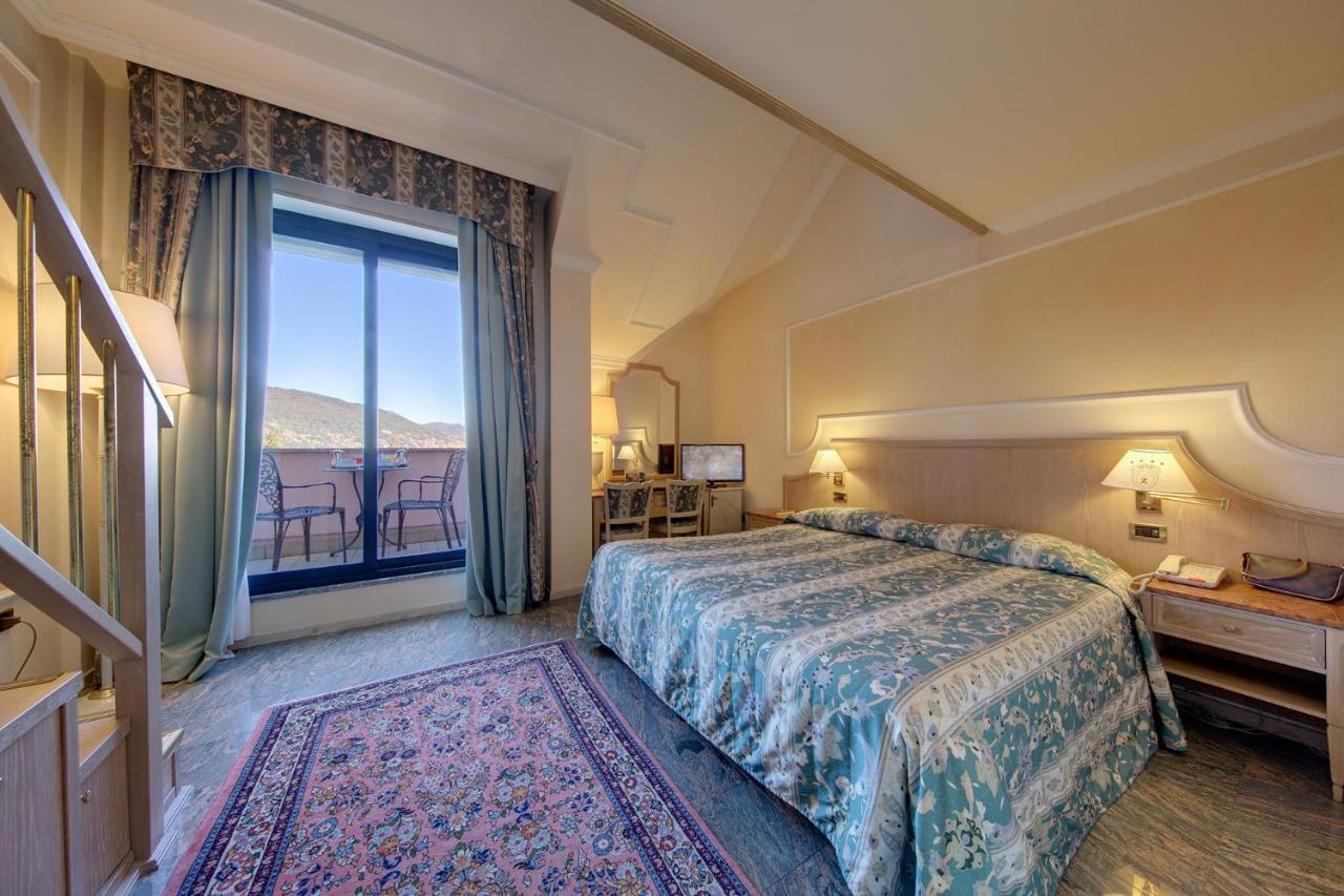een hotelkamer met een bed en een groot raam bij Hotel Simplon in Baveno