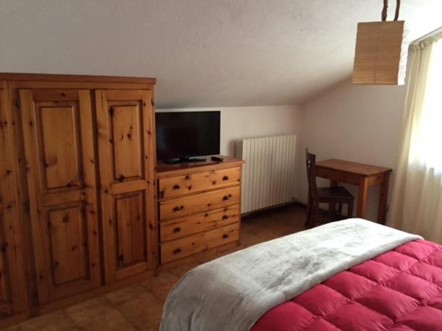 een slaapkamer met een bed en een commode met een televisie bij Hotel Sciatori in Sestriere