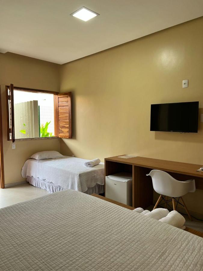 een hotelkamer met twee bedden, een bureau en een televisie bij Hotel do Carmo in Piracuruca