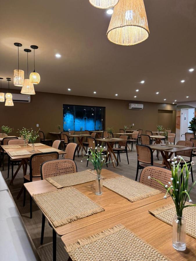 een restaurant met houten tafels en stoelen en verlichting bij Hotel do Carmo in Piracuruca