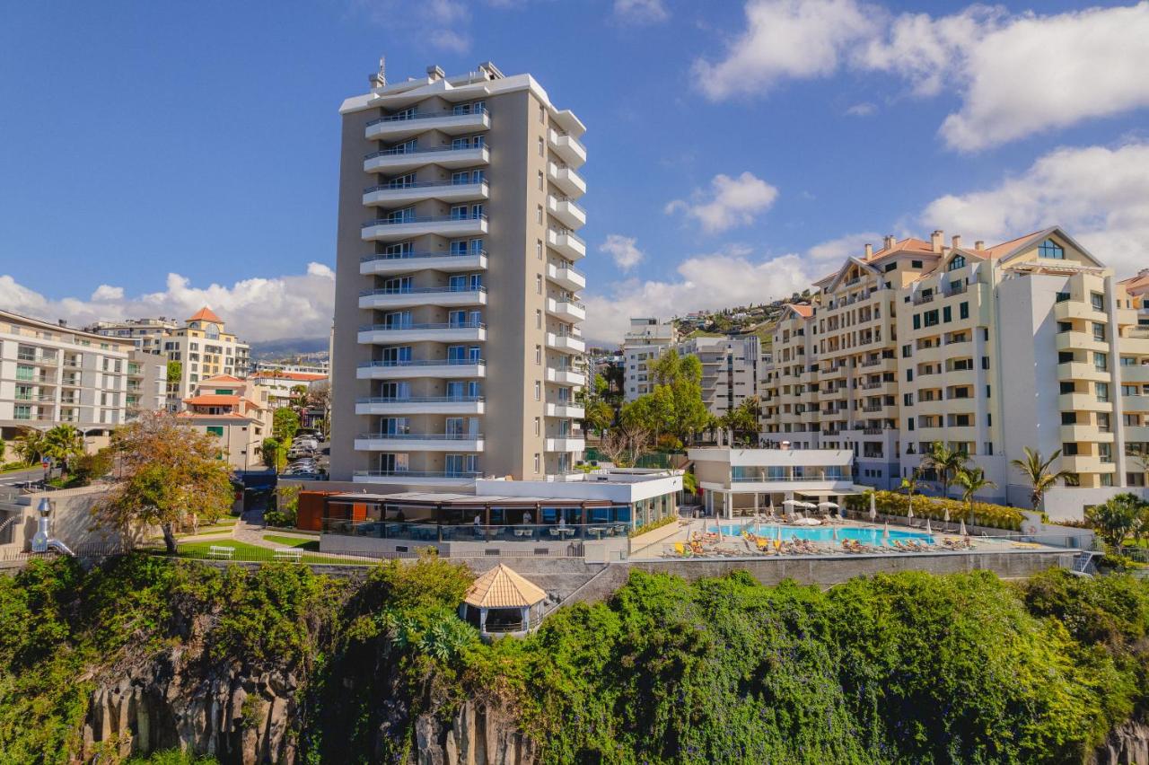 een hoog wit gebouw met een zwembad en bijgebouwen bij Duas Torres Hotel in Funchal