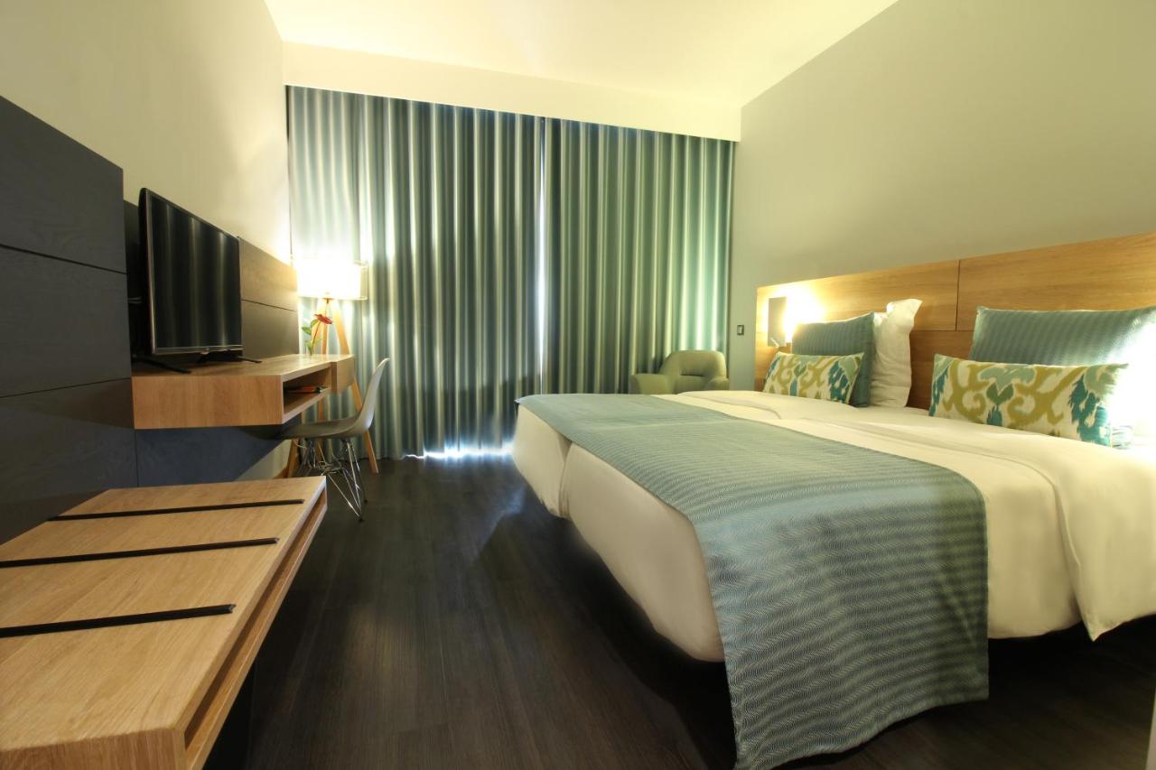 een hotelkamer met een groot bed en een televisie bij Madeira Panorâmico Hotel in Funchal