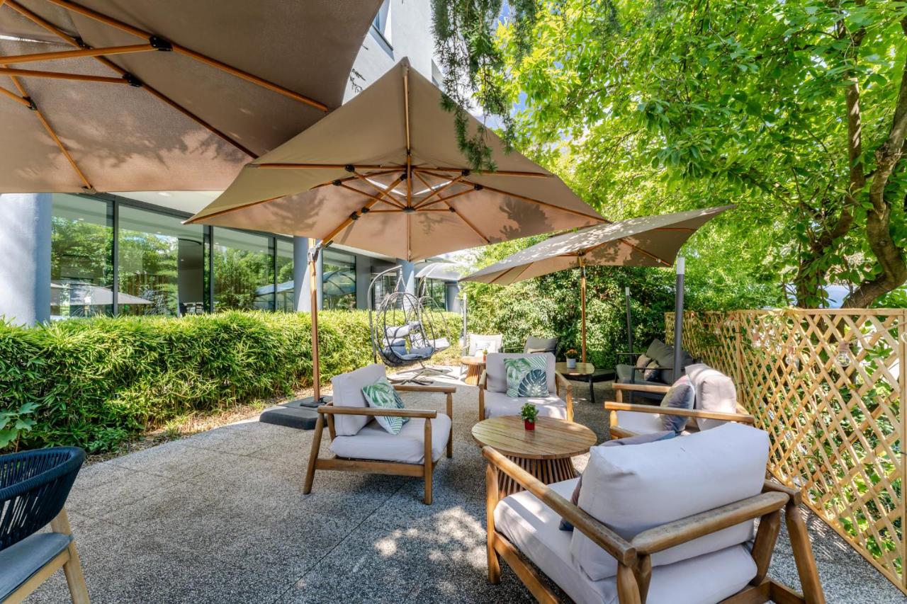 een terras met stoelen en tafels met parasols bij Acca Sporting Milano - AA Hotels in Opera