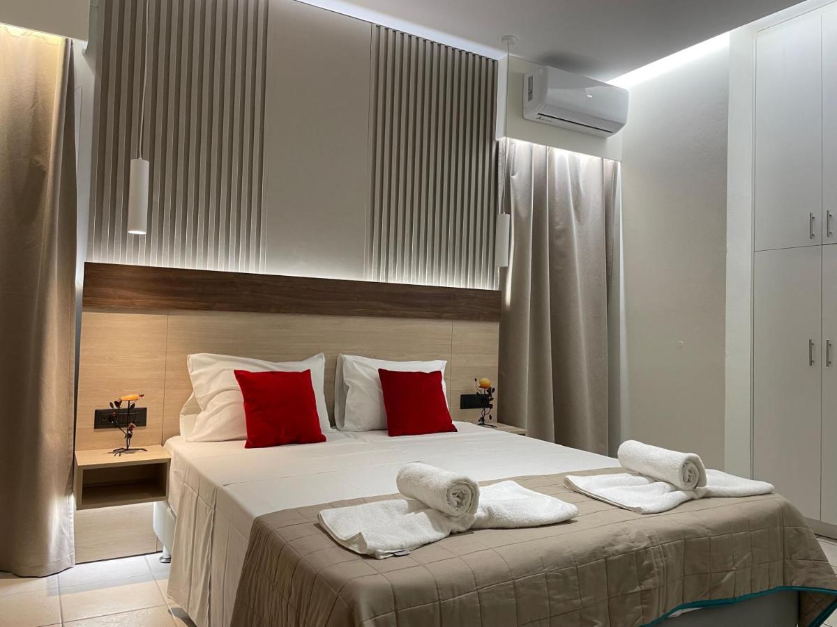 een slaapkamer met een groot bed met rode kussens bij Voula Hotel in Chersonissos