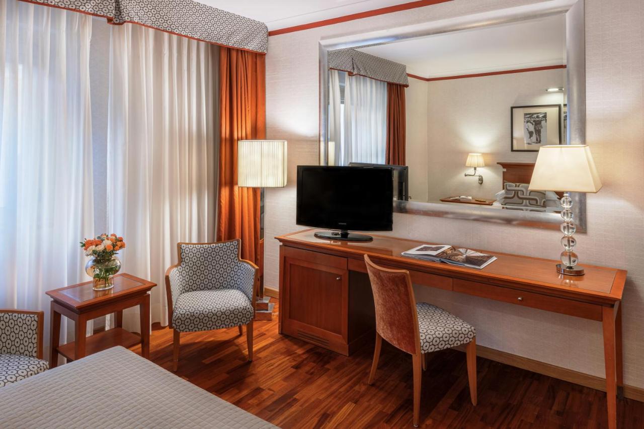 een hotelkamer met een bureau met een televisie en stoelen bij Starhotels Metropole in Rome