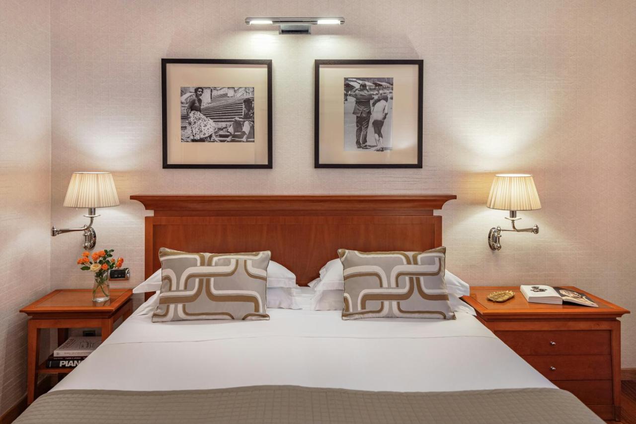 een slaapkamer met een groot bed en drie schilderijen aan de muur bij Starhotels Metropole in Rome