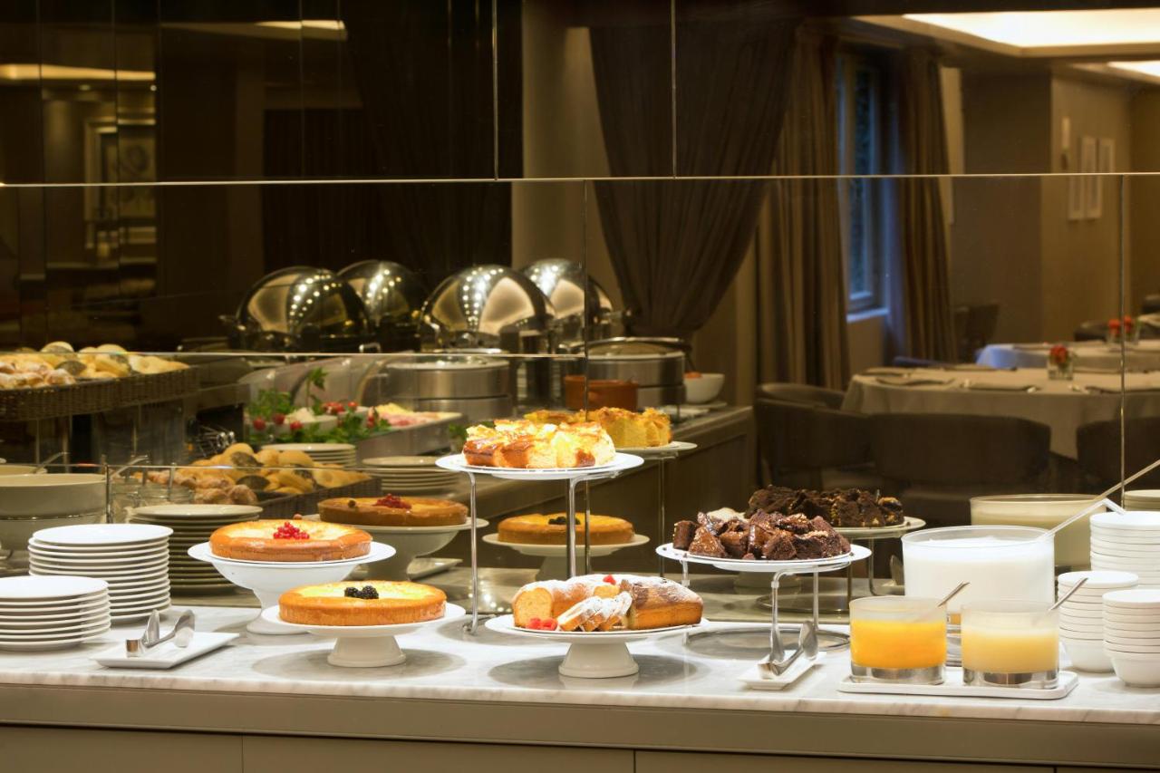 Een buffet met diverse gebakjes en desserts op borden. bij Starhotels Michelangelo Florence in Florence