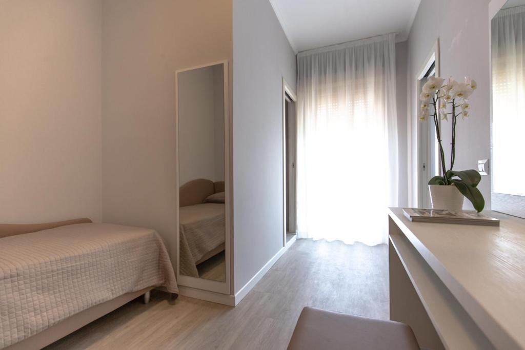 een slaapkamer met een spiegel naast een bed bij Hotel Susy in Rimini